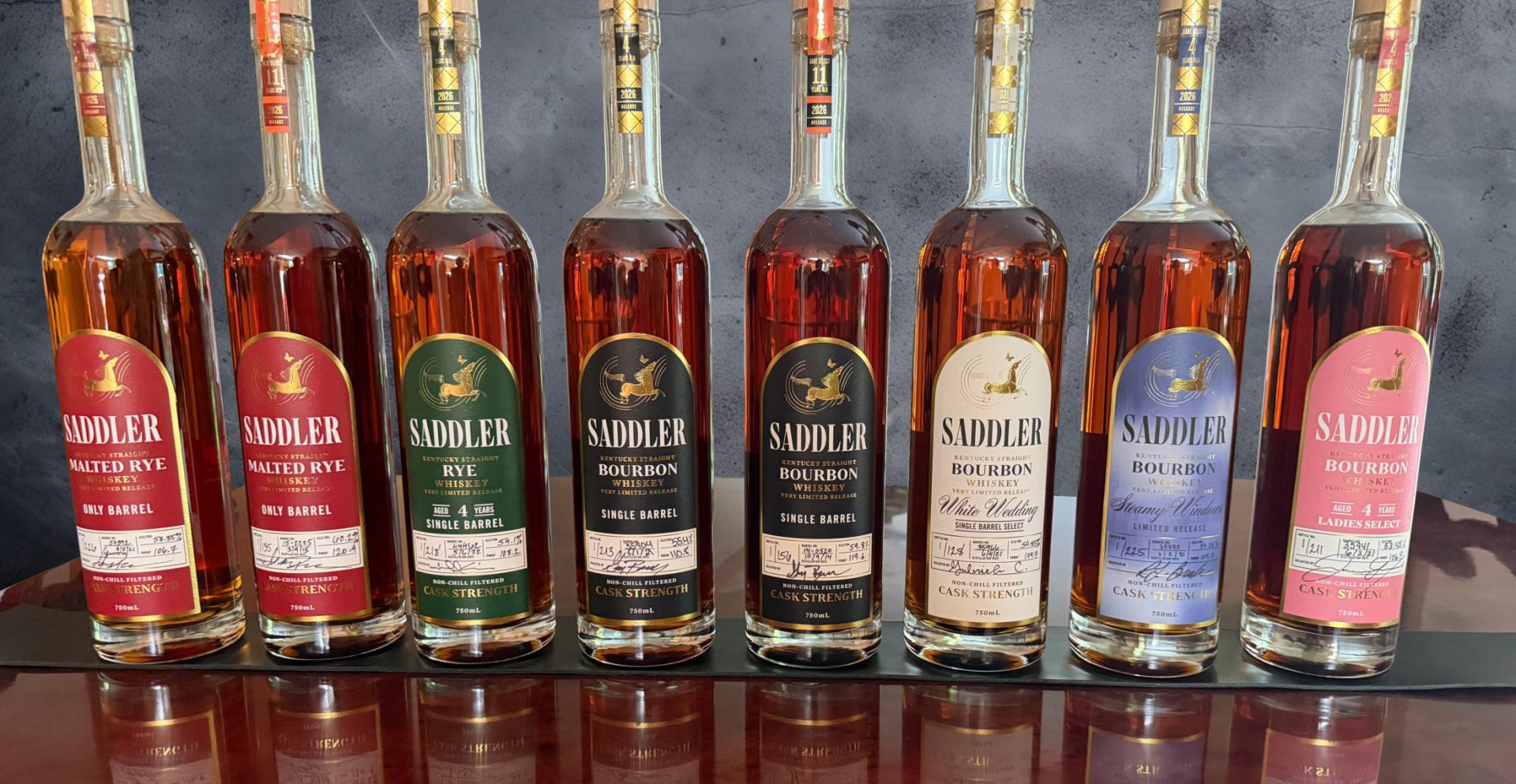 Eight single-barrel bourbon and rye bottles with foil-stamped custom labels, each hand-numbered