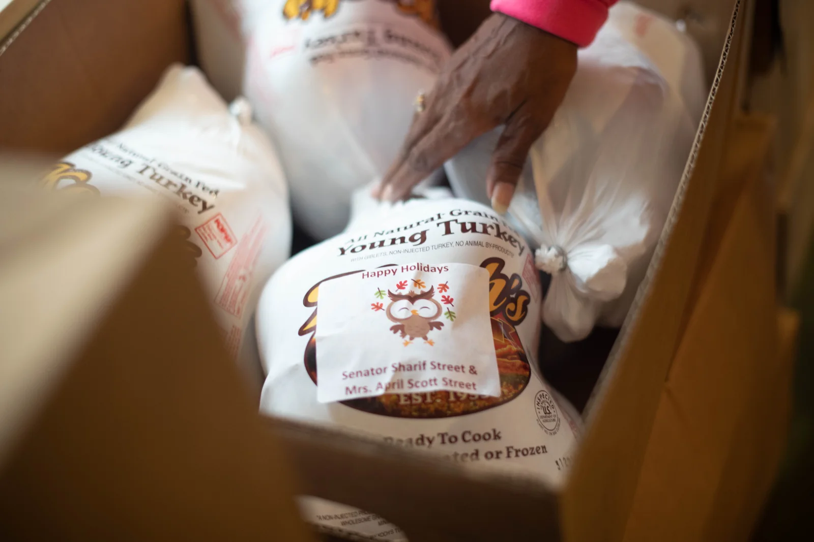 A printed Happy Holidays sheet label applied to a bagged frozen turkey in a shipping box